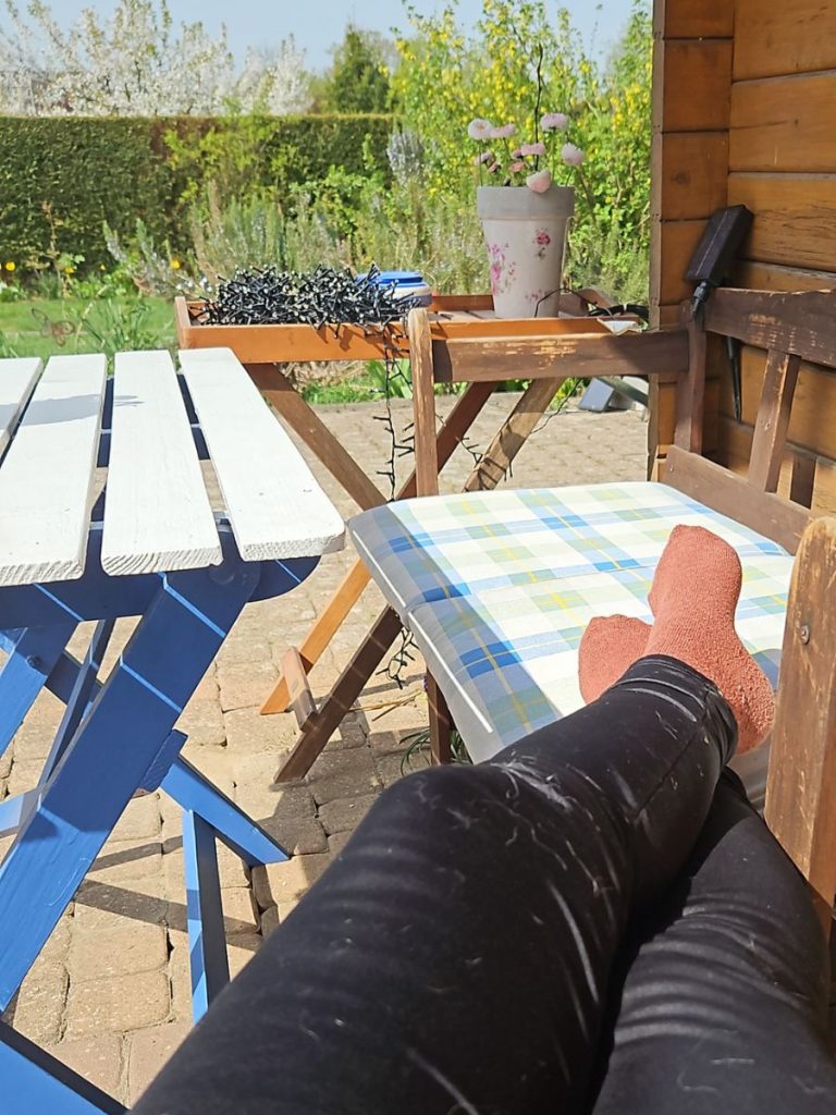 Person sitzt entspannt vor einer Gartenhütte mit Blick in den Garten