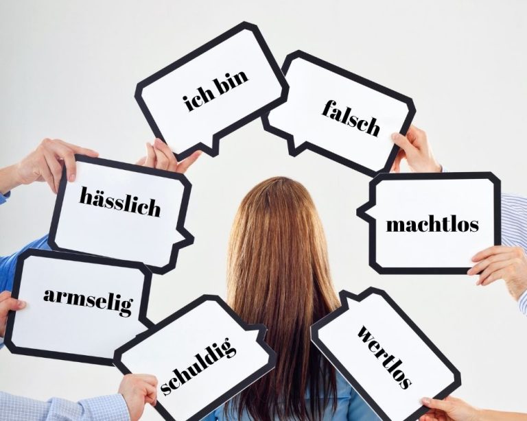 Eine Frau steht im Zentrum, umgeben von Armen, die ihr Sprechblasen mit negativen Worten wie "falsch", "hässlich" und "machtlos" entgegenhalten – Symbolbild für offensive Energien durch negative Suggestionen