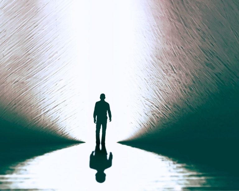 Die Silhouette eines Mannes geht aufrecht und selbstbewusst auf ein helles Licht zu – Symbolbild für Schutz vor offensiven Energien durch die eigene innere Kraft und Ausrichtung, mit der negative Einflüsse keine Resonanz finden