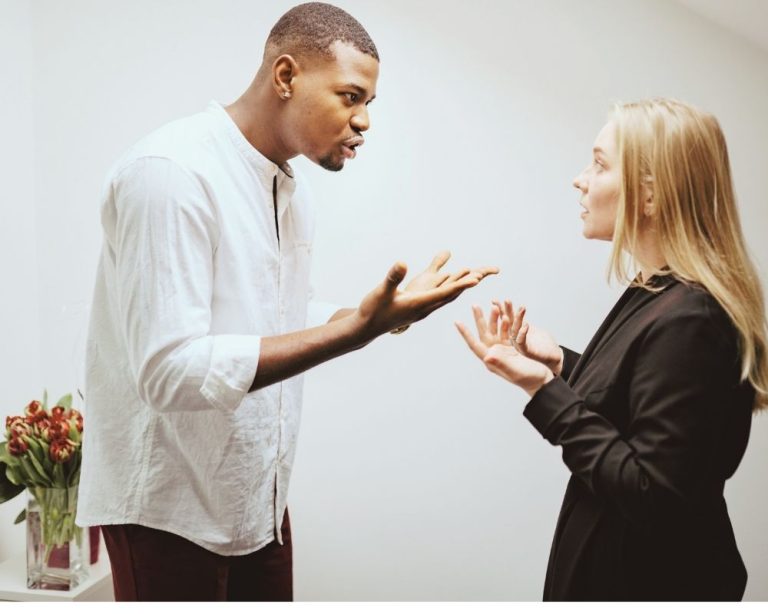 Ein größerer Mann steht dominant vor einer kleineren Frau und übt Macht über sie aus – Symbolbild für Sabotage, die jemanden von seinem eigentlichen Weg abbringen soll